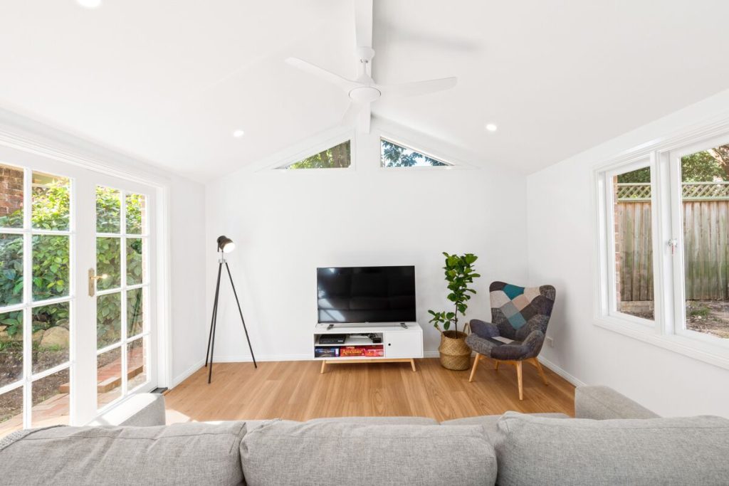 Bright living room with a vaulted ceiling, large windows and garden doors
