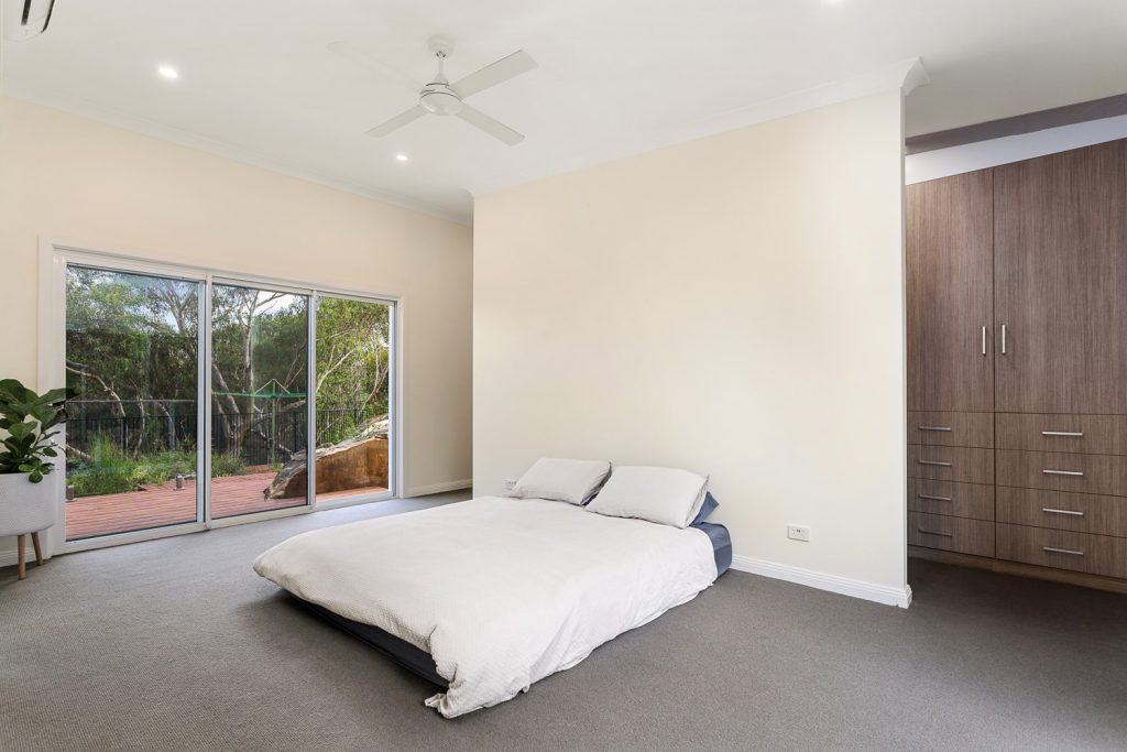 Completed master bedroom with carpet, built-in joinery and doors opening towards the deck