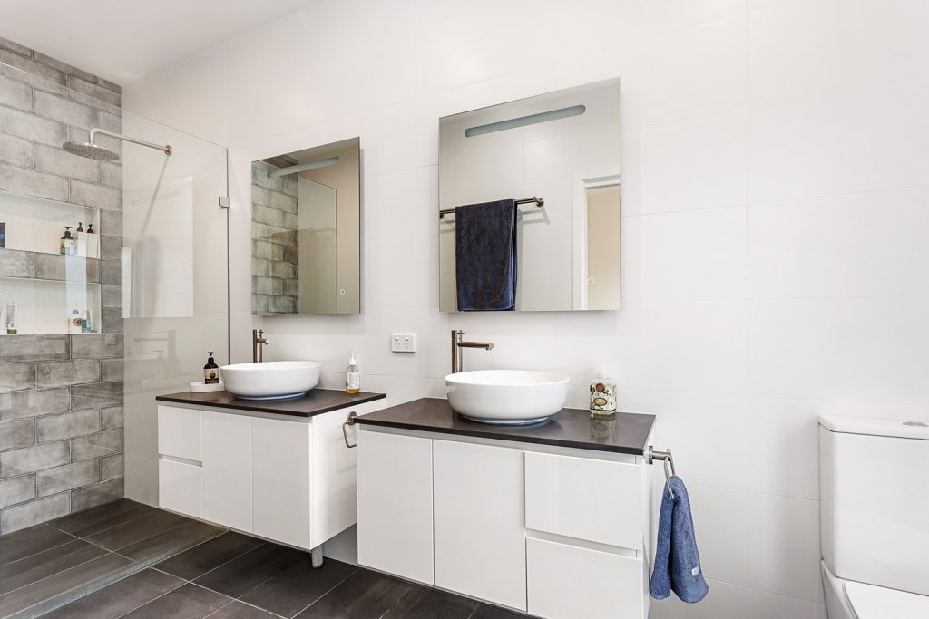 Completed ensuite with twin basins, wall-hung vanities and a tiled shower