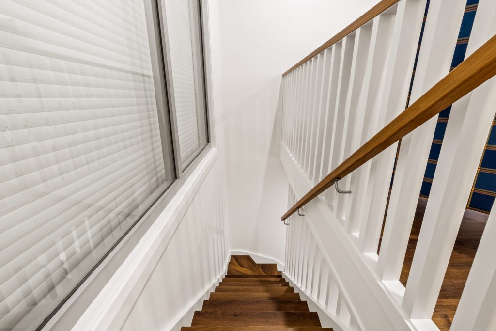 View down the new internal staircase, with white balusters, timber handrails and a window beside the stairs.